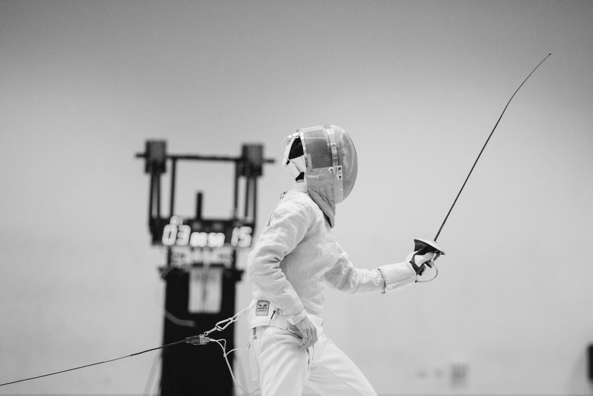 Person wearing white coveralls holding fencing sword